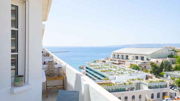 Un balcon avec vue sur la mer, un espace piscine et un immeuble doté de nombreux balcons.