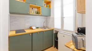 Une petite cuisine équipée d’un évier, d’un grille-pain et d’une fenêtre avec des stores.