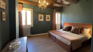 Un dormitorio con cama, cabecera de madera, candelabro y cuadros en la pared.