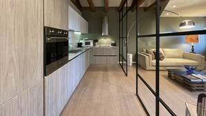 Una cocina moderna con vigas de madera, horno empotrado y microondas.