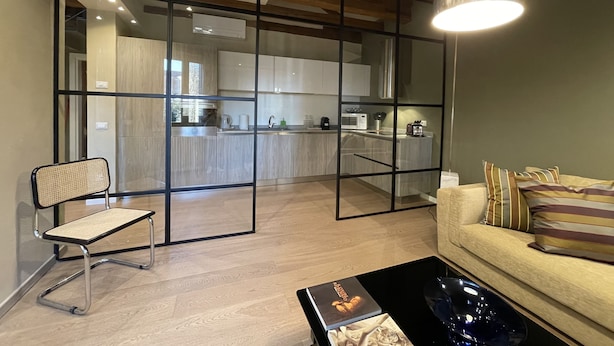 Una sala de estar moderna con un separador de vidrio, un sofá, una mesita de centro y un sillón.