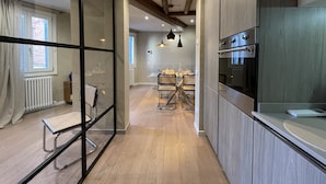 Una cocina moderna con suelo de madera, horno empotrado e iluminación colgante.