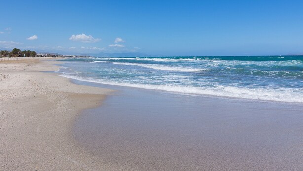 Ein Strand mit breitem Sandstrand und sanften Wellen.