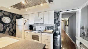 A modern kitchen with white cabinets, a microwave, a coffee maker, and a clock on the wall. - 3 Bedroom Condo on the beach. (Murrells Inlet)