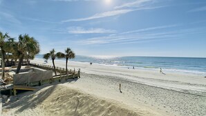A beach with palm trees, a wooden boardwalk, and a clear sky. - 3 Bedroom Condo on the beach. (Murrells Inlet)