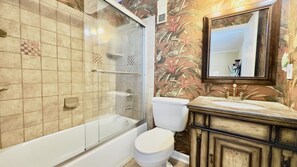 Ein Badezimmer mit Duschkabine, weißer Toilette und Waschtisch mit Spiegel.