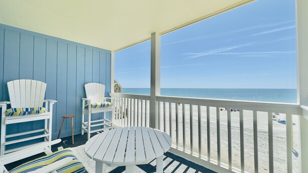 A beachside balcony with white Adirondack chairs and a small table, overlooking a sandy beach and the ocean. - 3 Bedroom Condo on the beach. (Murrells Inlet)