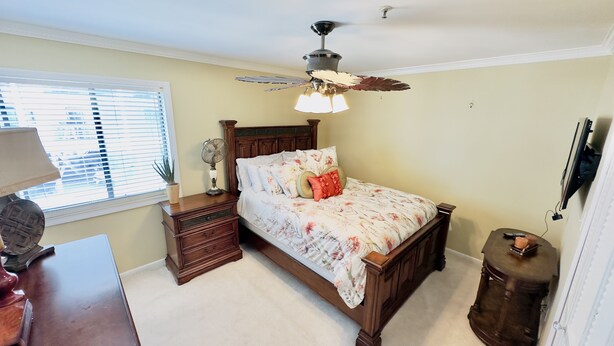 A bedroom with a bed, a nightstand, a dresser, a ceiling fan, and a window with blinds.