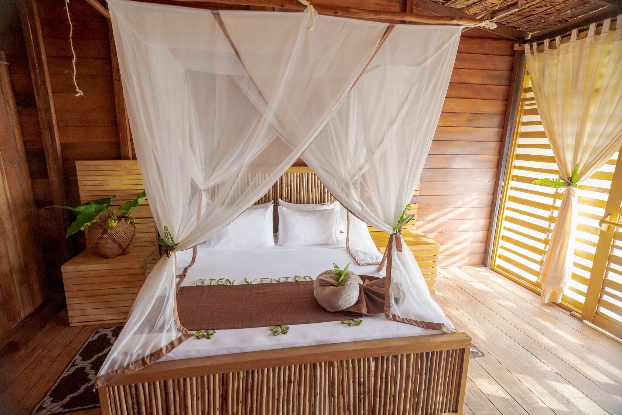 A bed with a canopy, wooden walls, and a window with blinds.