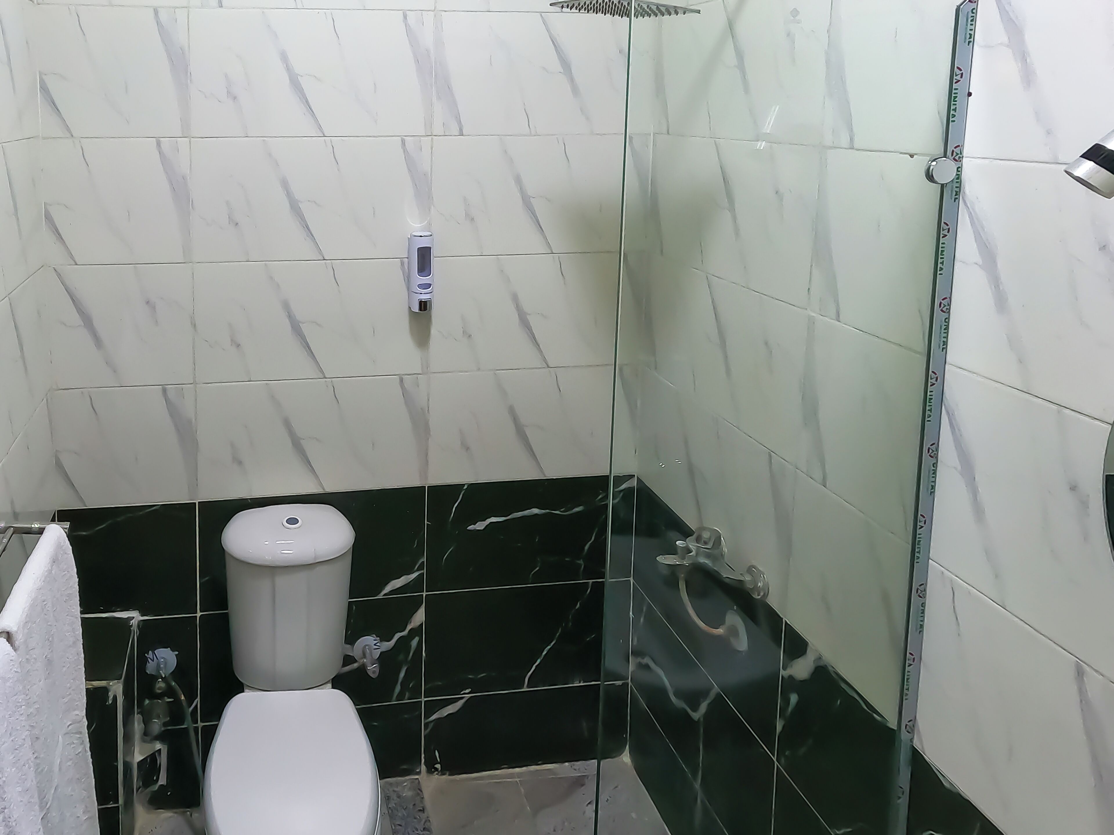 Un baño con inodoro, ducha y cabina de ducha de vidrio.