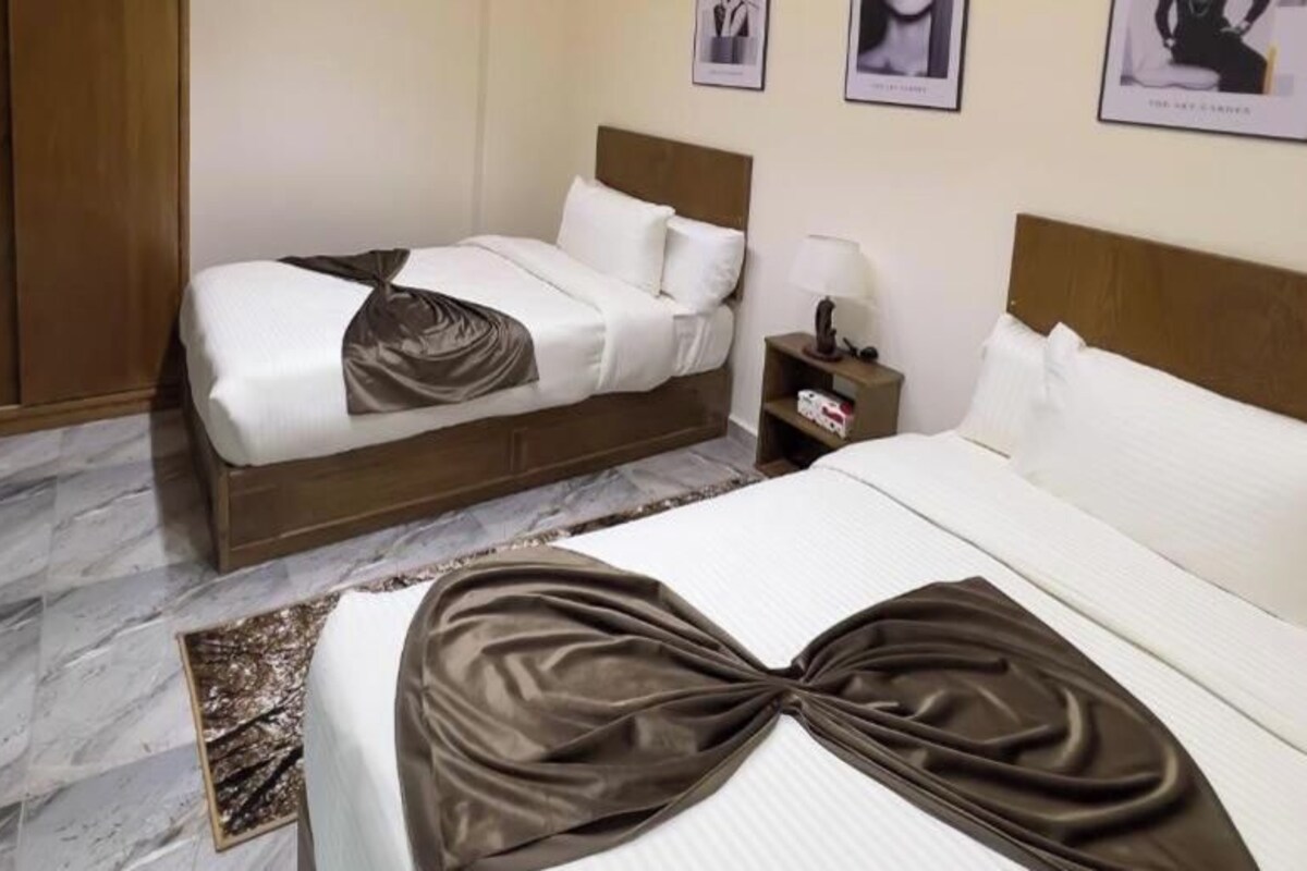 Habitación de hotel con dos camas, un armario de madera, una mesita de noche y un cuadro en la pared.