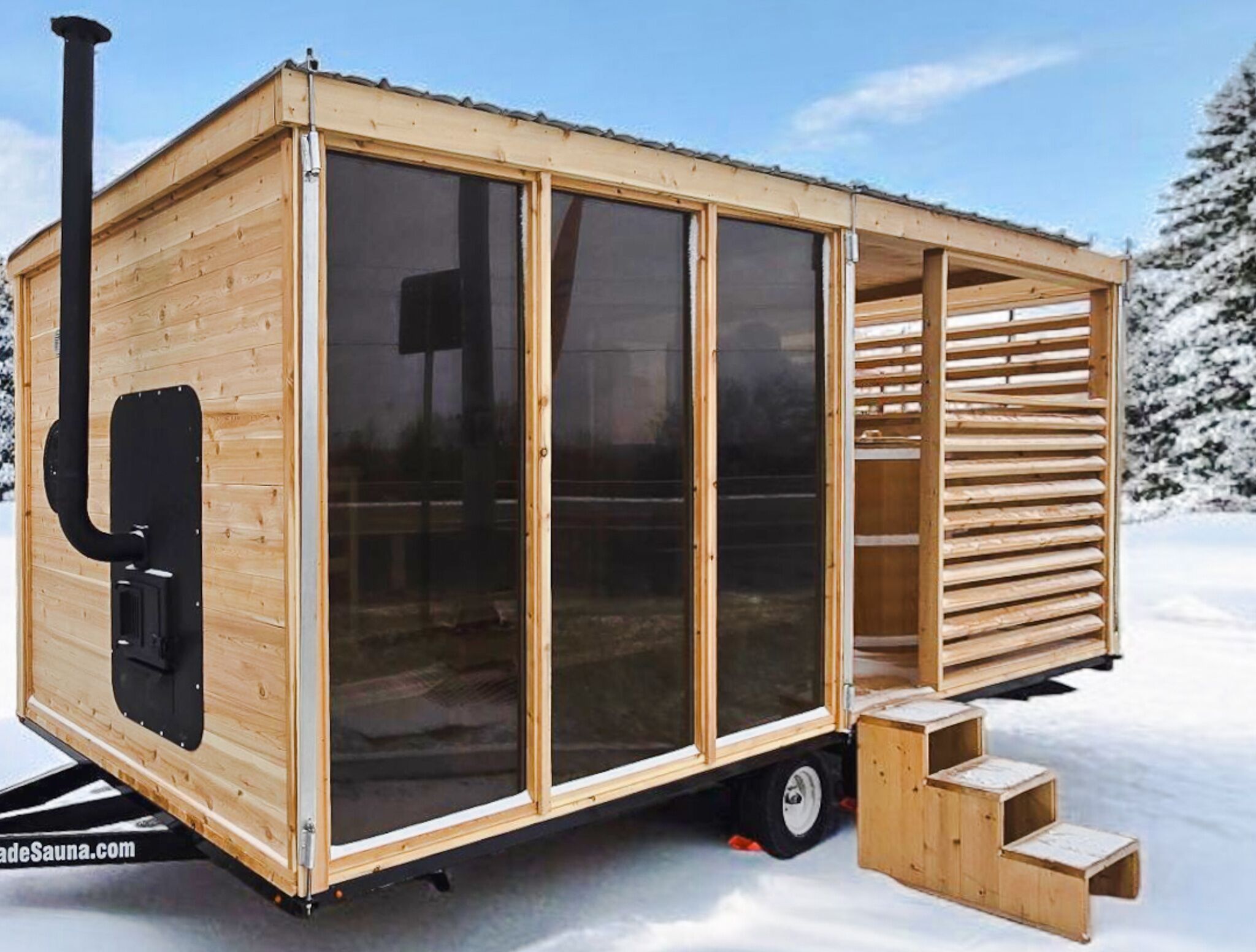 A wooden mobile sauna with large windows and a chimney, set on a trailer.