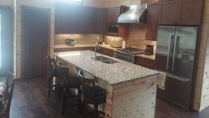 A modern kitchen with wooden paneling, stainless steel appliances, and a granite countertop.