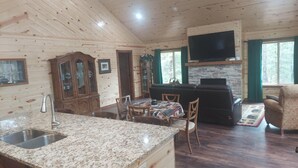 A wooden cabin interior with a kitchen, dining area, and living room.