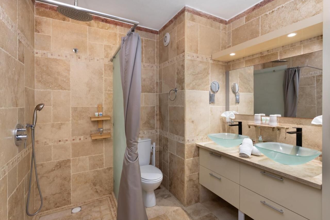 Une salle de bain équipée d’une douche, de toilettes et de deux lavabos avec des cuves en verre.