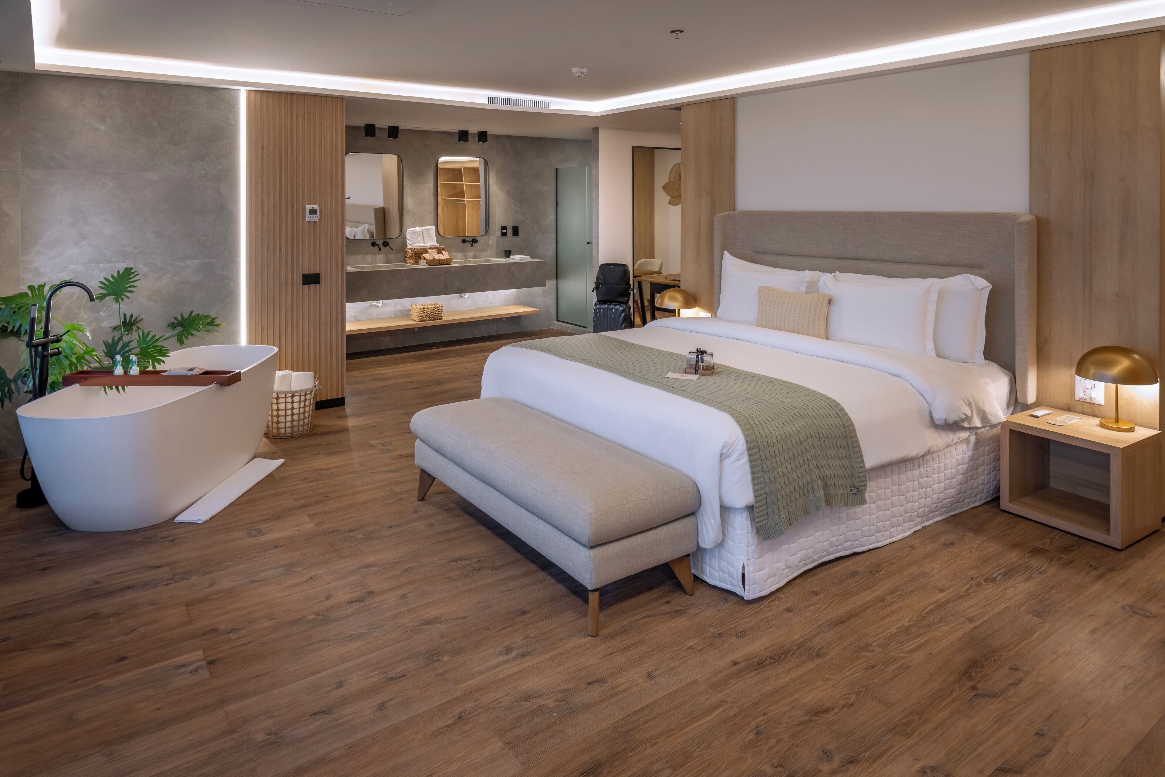 Un dormitorio de hotel moderno con una cama grande, una bañera y un tocador con espejo.