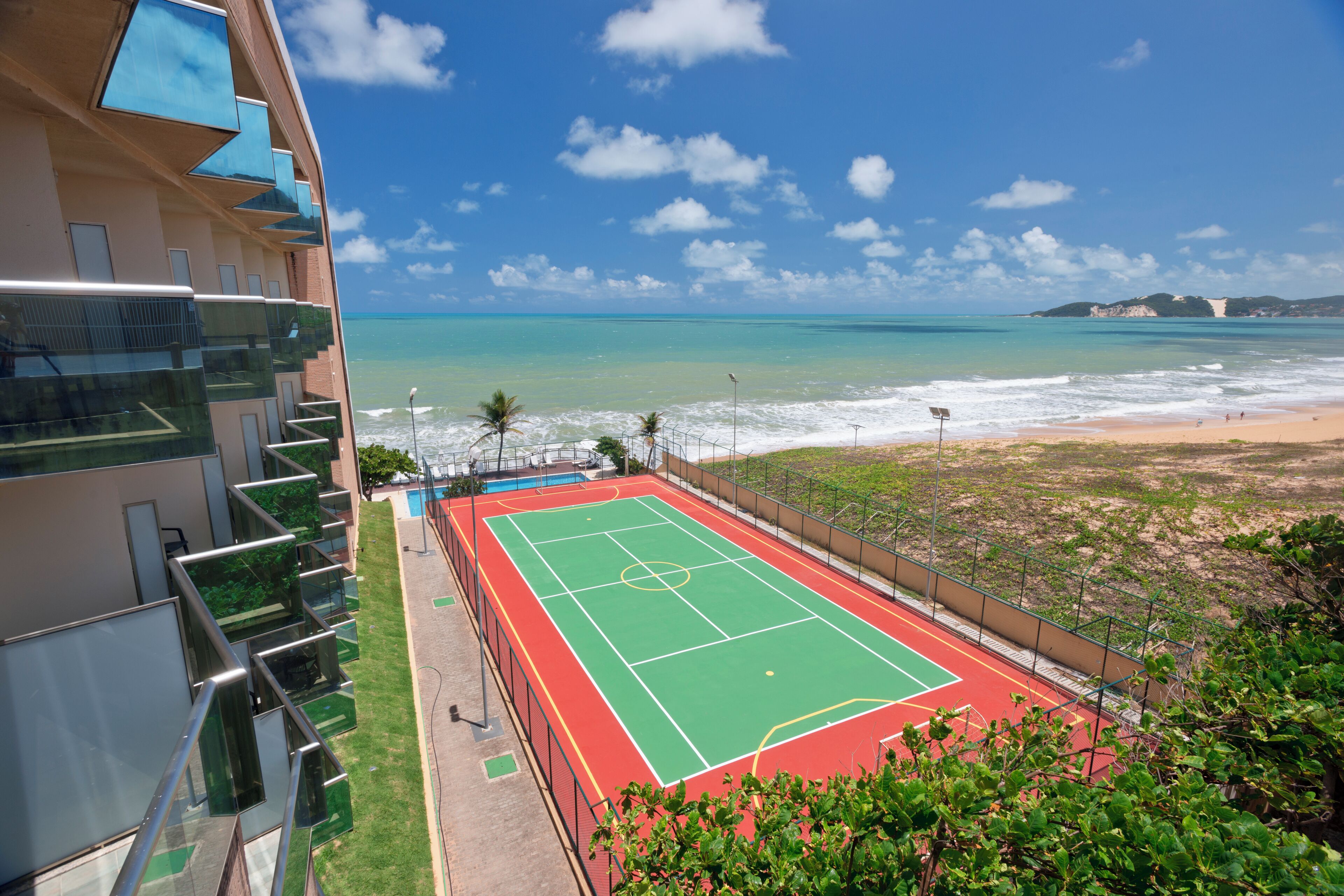 Una cancha de tenis con vistas a la playa y al océano.