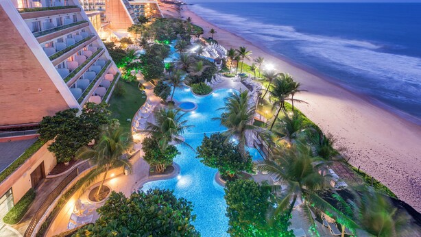 A resort with a swimming pool, palm trees, and a beach view. - SERHS Experience Suites (Natal)