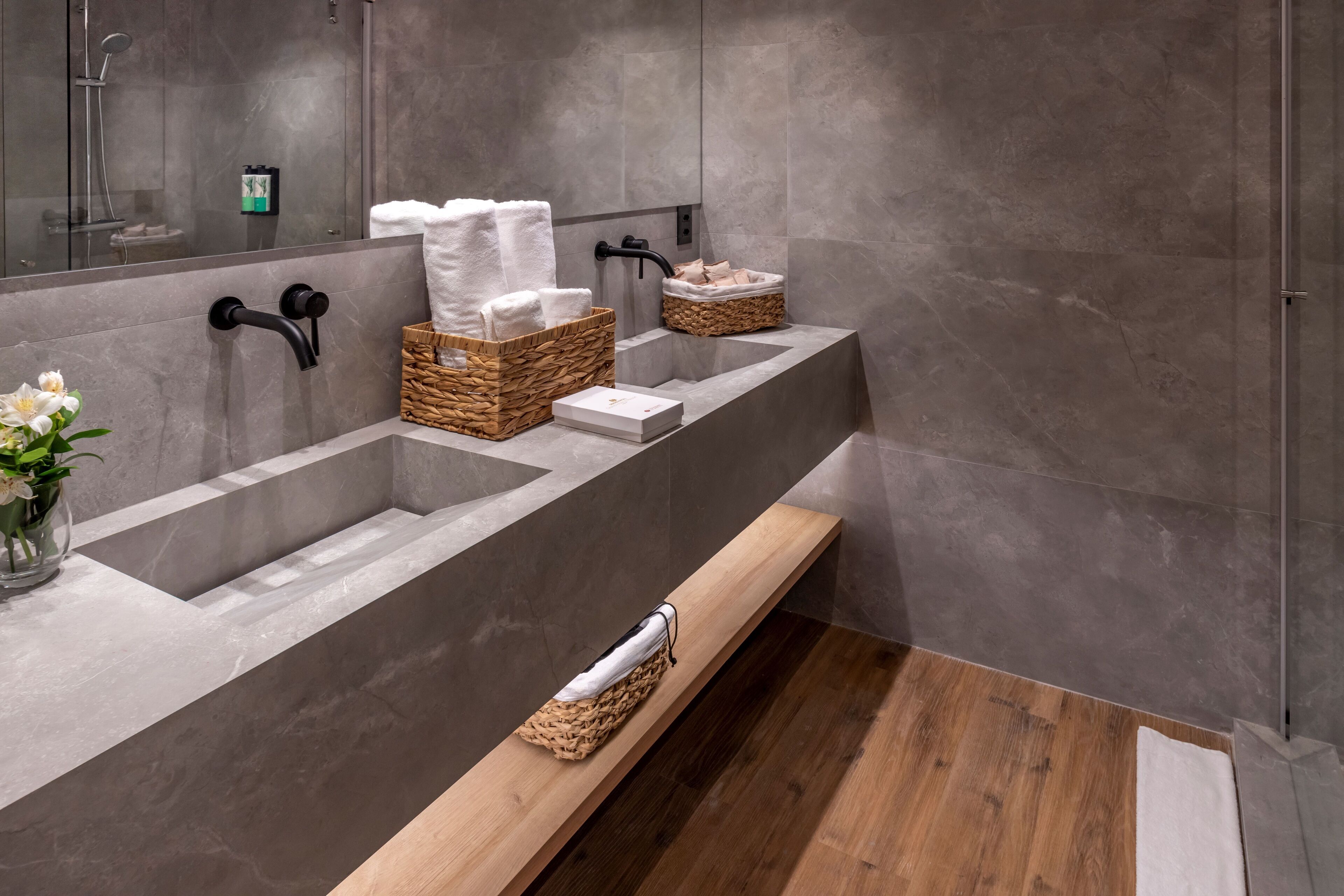 Un baño moderno con dos lavamanos, un estante de madera y un espejo grande.