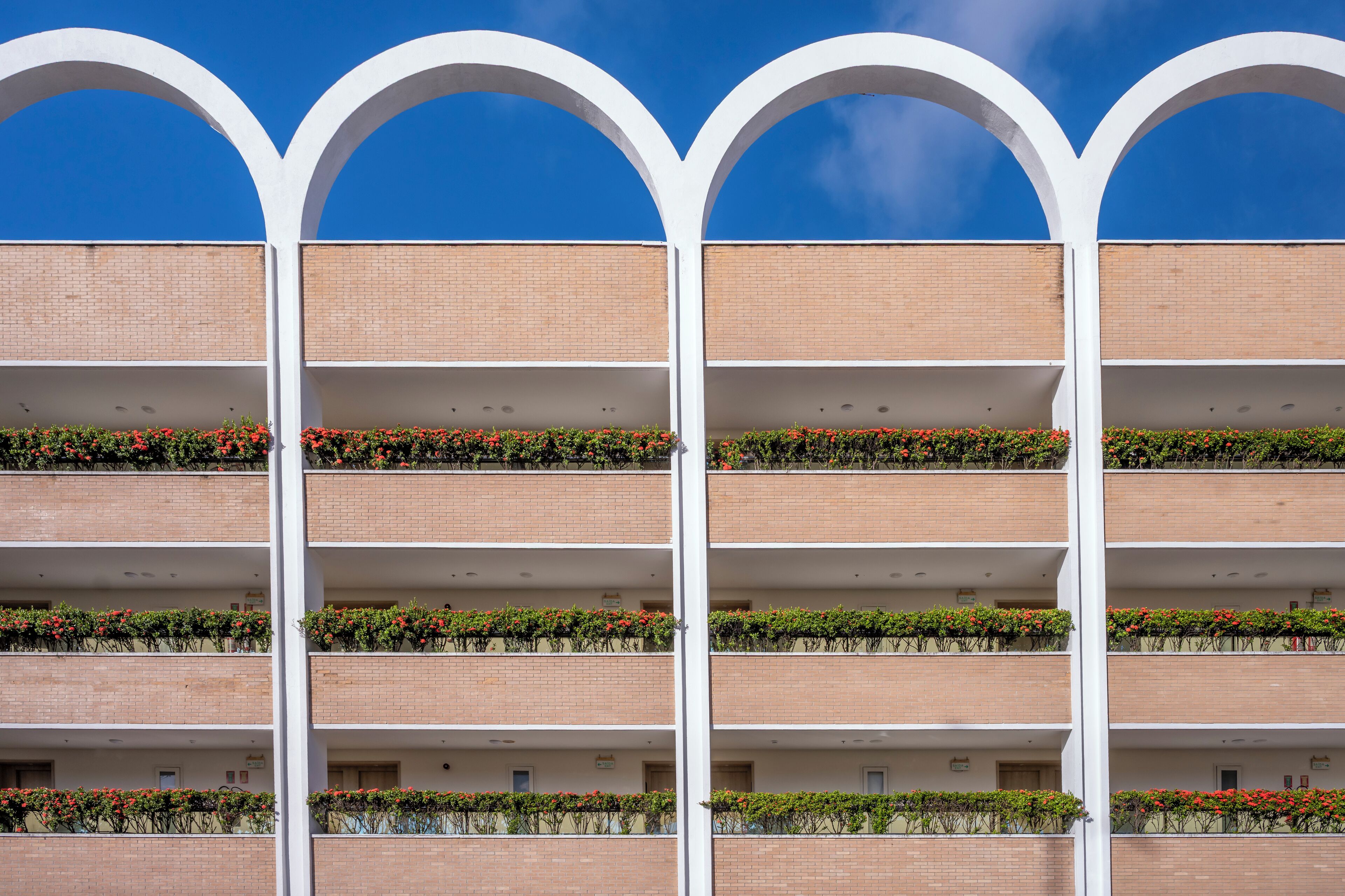 Un edificio de varios pisos con fachada de ladrillo y arcos blancos en la parte superior.