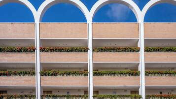 Un edificio de varios pisos con fachada de ladrillo y arcos blancos en la parte superior.