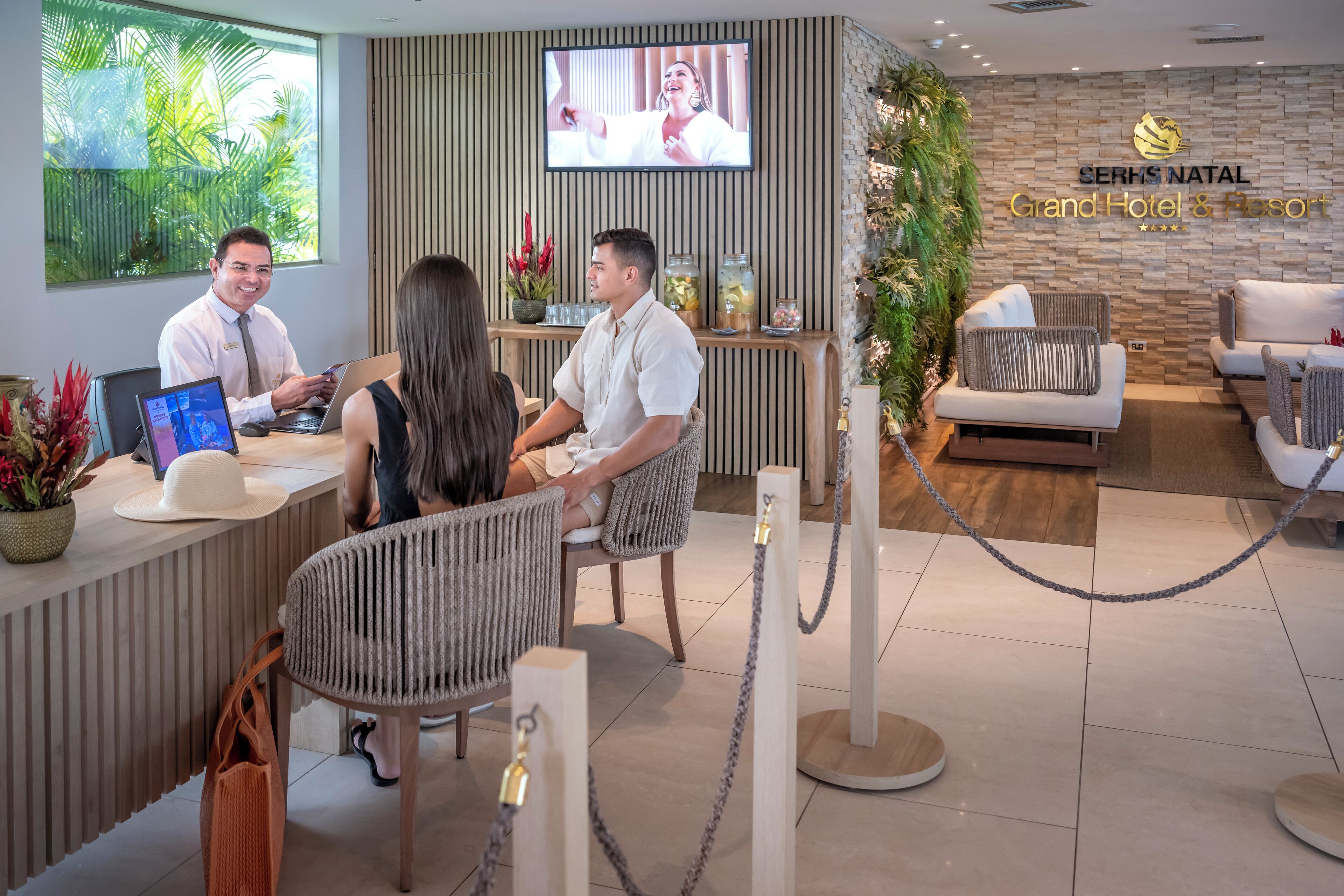A reception area with a reception desk, a television screen, and a seating area with a sofa and chairs.