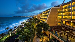 A hotel with multiple balconies overlooking the ocean, a pool area, and a beach view. - SERHS Experience Suites (Natal)