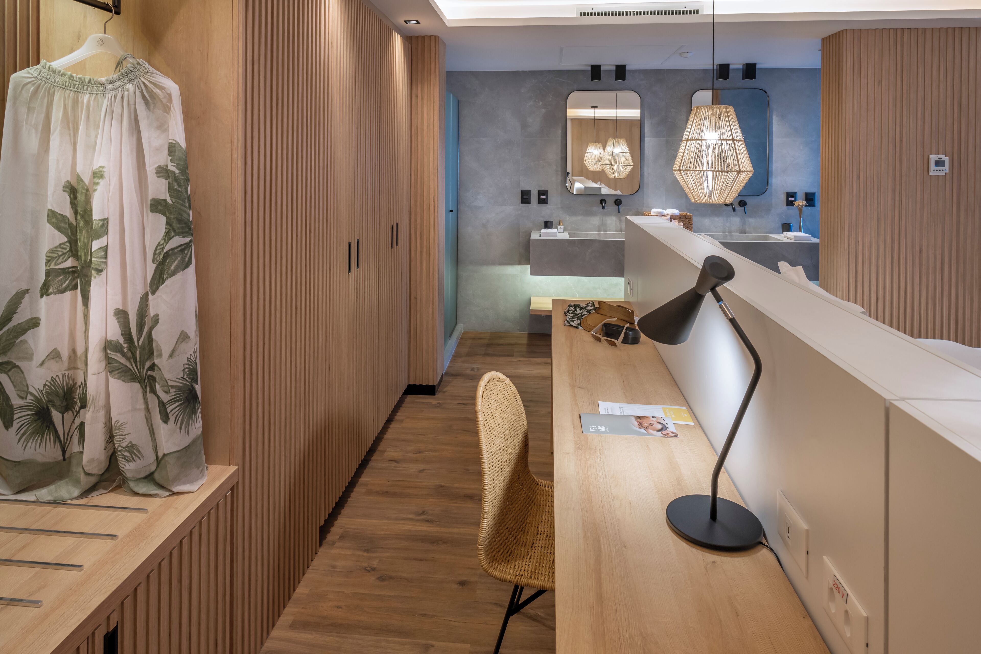 Un baño moderno con armarios de madera, un espejo grande y una lámpara colgante elegante.