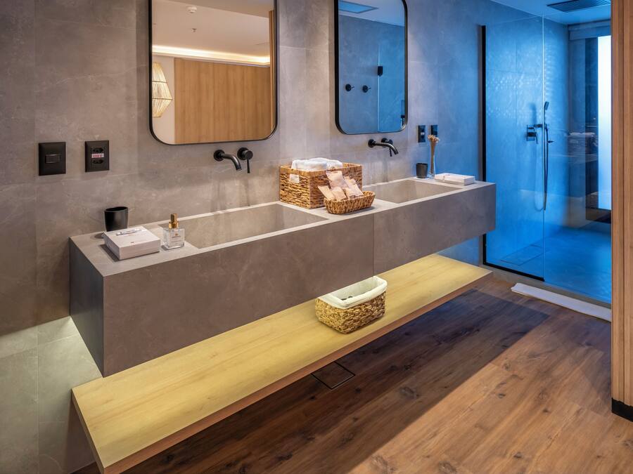 A modern bathroom with a long vanity, two sinks, and a bench.