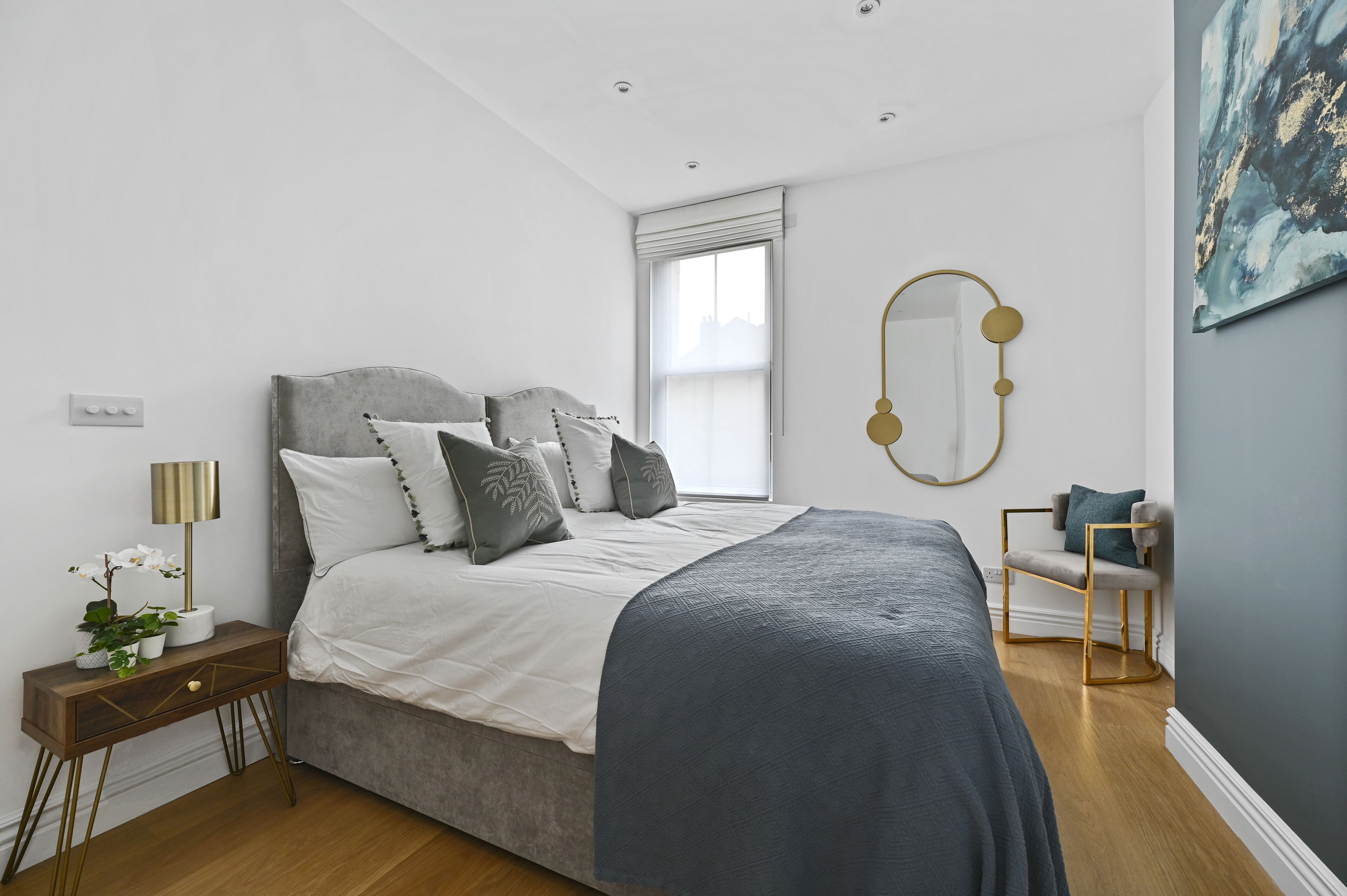 Quarto com cama, mesa de cabeceira, luminária e uma cadeira.