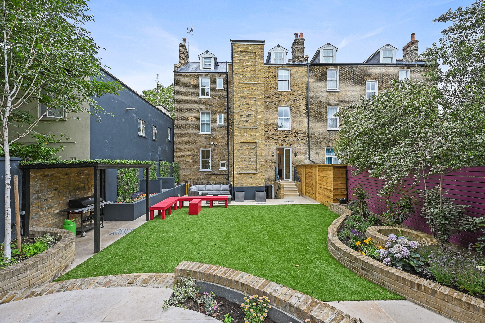 A residential backyard with a lawn, patio furniture, and a brick wall.