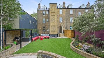 A residential backyard with a lawn, patio furniture, and a brick wall.