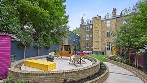 Une terrasse circulaire dotée d’une balançoire, de sièges et d’un jardin surélevé.