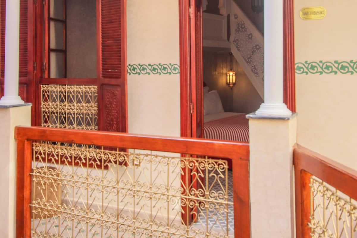 A traditional room with a balcony, a staircase, and a decorative lantern.