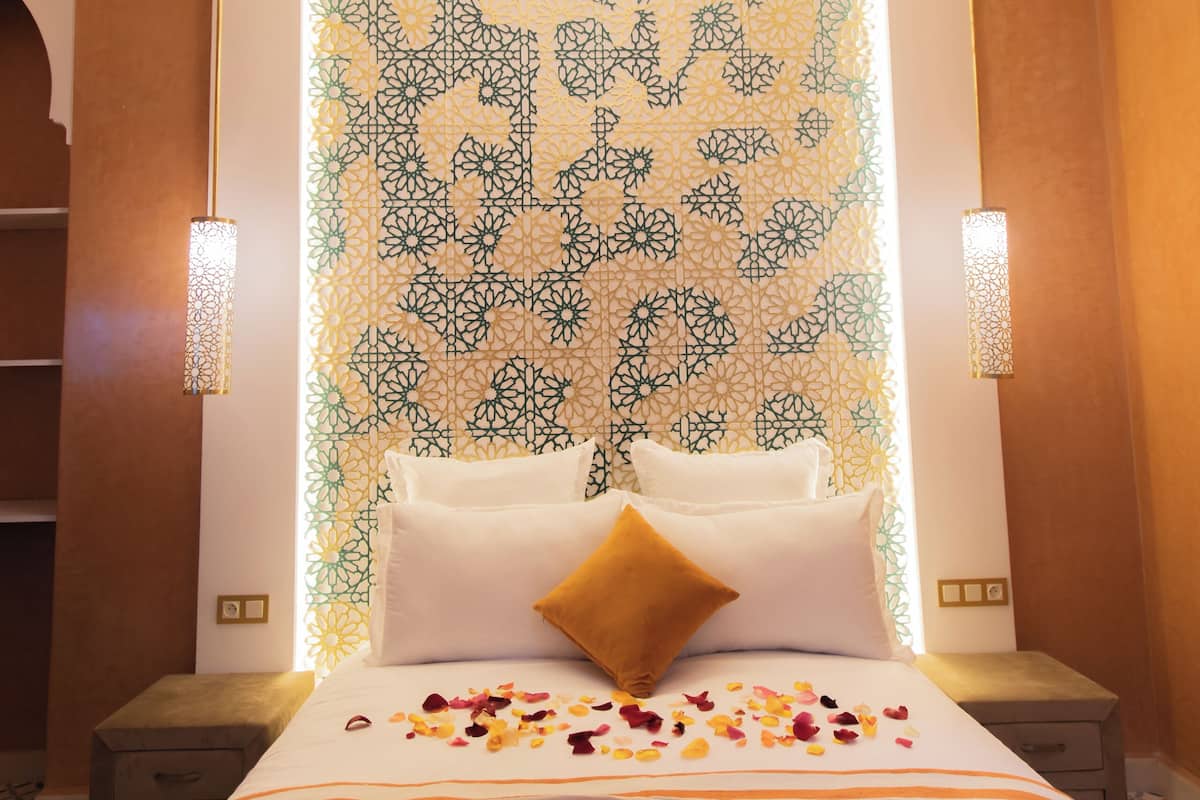 A hotel room with a large bed, decorative wall, and two bedside lamps.