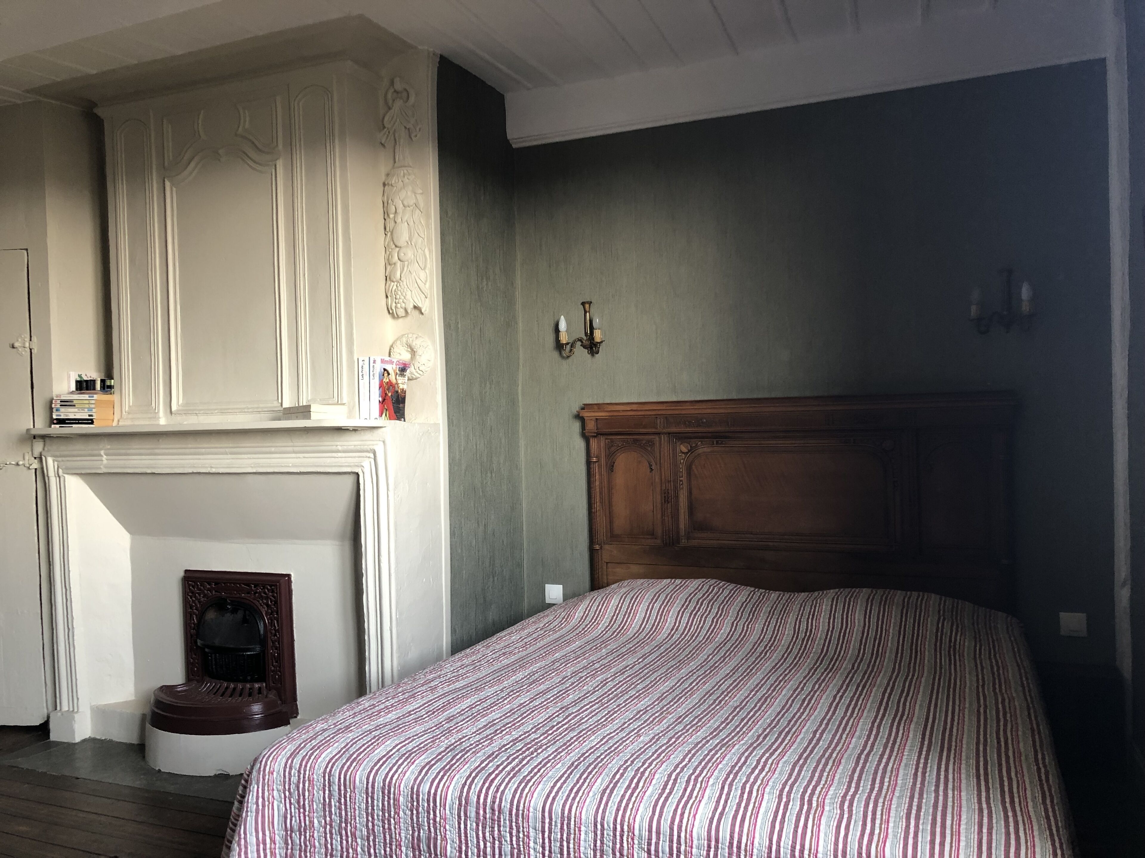 Un dormitorio con cama, chimenea y cabecero de madera.