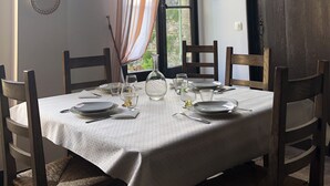A dining table set with plates, glasses, and a vase, surrounded by wooden chairs. - Maison Ancienne Avec son Jardin Privatif (Le Havre)
