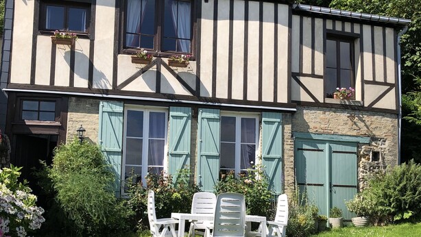 A traditional half-timbered house with a stone facade, a small garden with a table and chairs, and a blue door. - Maison Ancienne Avec son Jardin Privatif (Le Havre)