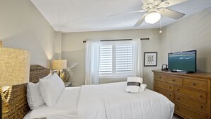 A bedroom with a bed, a wooden dresser, a television, and a ceiling fan. - Mainsail 362 - Gulf Front Condo, Community Pool, Hot Tub, Free Beach Service! (Miramar Beach)