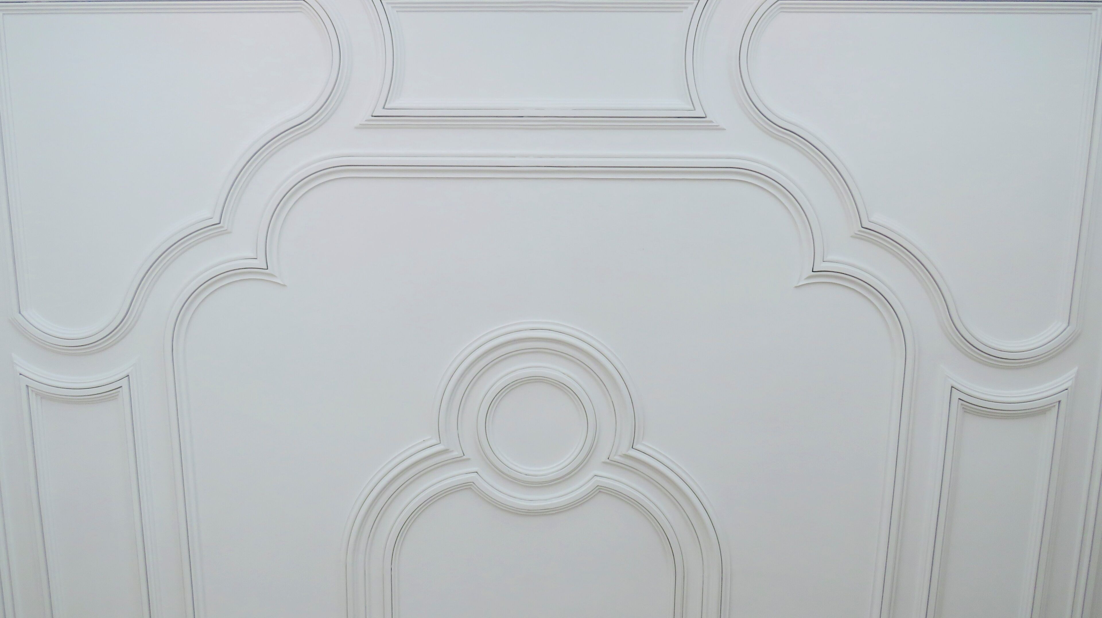 A white wall with decorative molding and a central circular design.