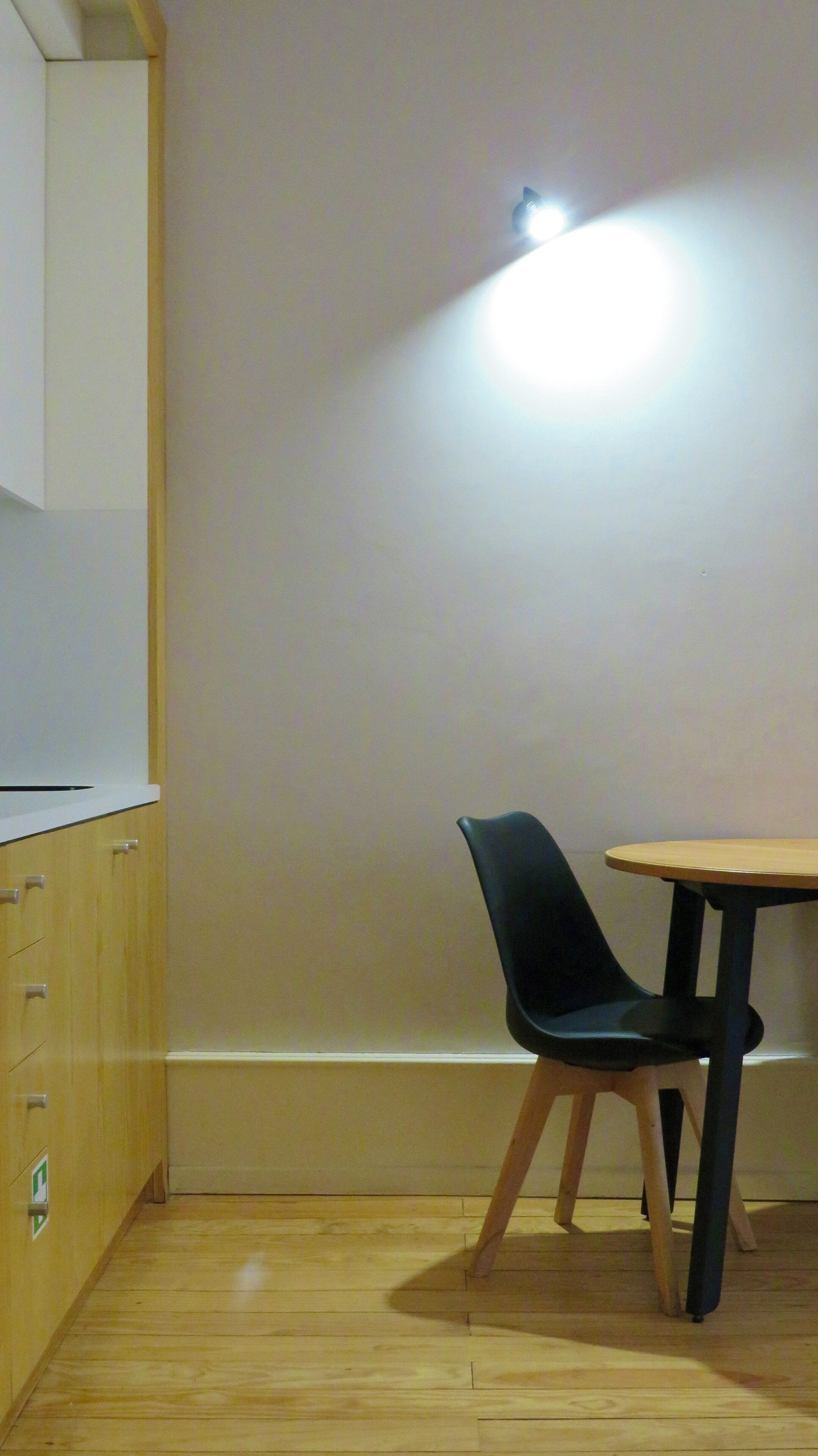 Un pequeño comedor con una mesa de madera y una silla negra.