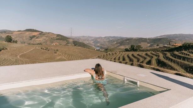 Una persona en una piscina rectangular con vistas a campos escalonados y colinas al fondo.
