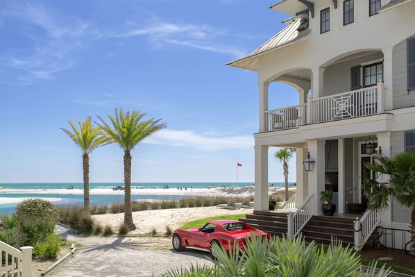 A beachfront property with a red sports car parked in front, a white building with a balcony, and a clear view of the ocean. - Gulfstrand Down - Gulf View, Heated Community Pool, Grayton Beach, 30A! (Grayton Beach)