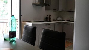 Una cocina moderna con estufa integrada, campana extractora y ventana con vistas a un balcón.