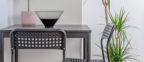 A modern chair with a perforated backrest and a table with a pink vase and a black bowl.