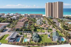 A resort with multiple buildings, a large pool, and a view of the ocean.