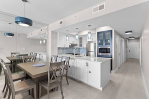 A modern kitchen with white cabinetry, a central island, and pendant lighting.