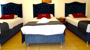 A hotel room with three beds, each with a dark headboard and a red pillow. The room has a tiled floor and a painting above the beds. - Hotel Feimar (Cusco)