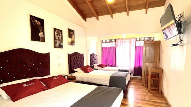 A hotel room with two beds, wooden flooring, a TV mounted on the wall, and a ceiling fan. - Hotel Feimar (Cusco)