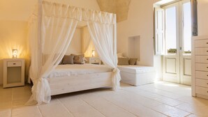 A bedroom with a four-poster bed, bedside tables, a nightstand, and a dresser. - Masseria Macchiaforte (Gallipoli)